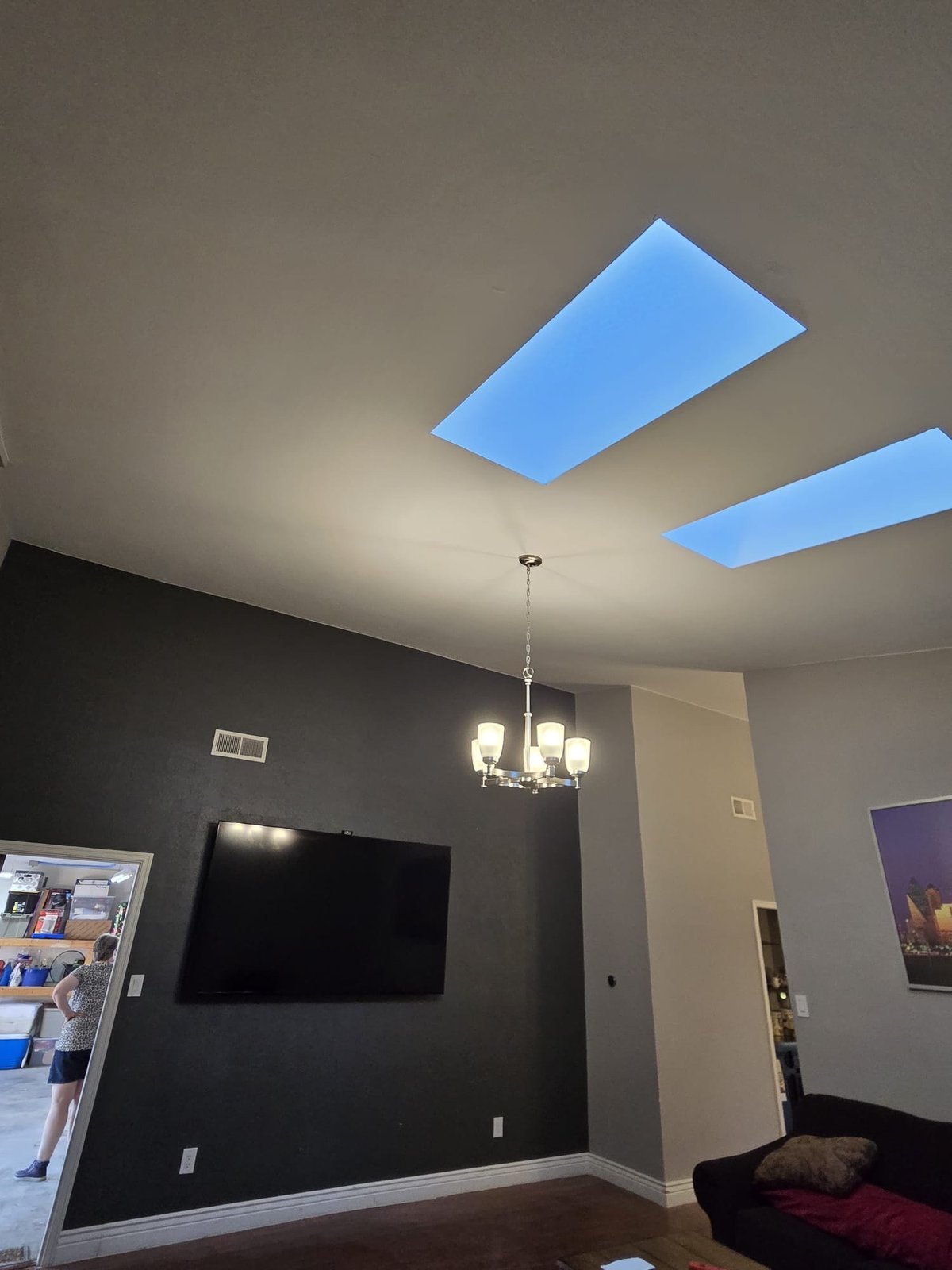 TV mounted in living room with chandelier and skylights